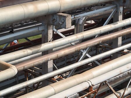 Diagonal tangle of pipes and reinforced concrete supports. Concept of complexity of petrochemical industry communications. Pipe weaving of various diameters, with expansion joints and flanges.の写真素材
