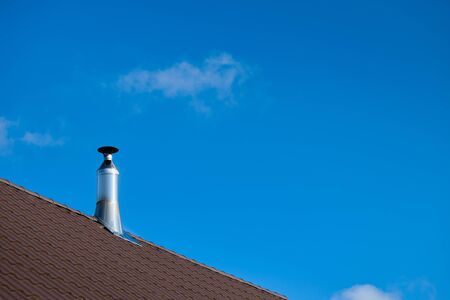 Modern style chimney from oven or fireplace stacked stainless steel on tiled roof made according to fire safety requirements, and to avoid condensation when reaching dew point in flue gases.の写真素材