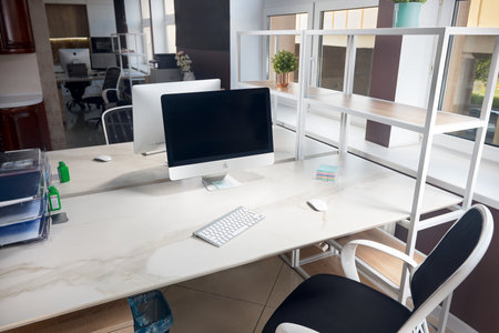 GRODNO, BELARUS - MAY 2020: Two Apple computer in office table with blank displays with stoneware table top, modern workplace of trendy office in loft style. Illustrative editorial.のeditorial素材