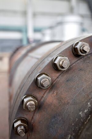 Bolted screw connection on manhole of industrial machine compressor or pump on chemical plant selective focus with out of focus abstract industrial background vertical with copyspace.の写真素材