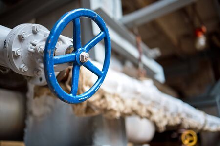 Industrial pipeline flanges blue hand wheel and valve close up, blur industrial pipelines background. Old rusty control equipment, abandoned plant industry, with copyspace.の写真素材