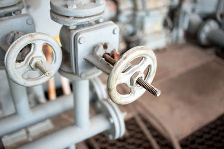 Industrial blue painted pipeline flanges, hand wheel and two valves closeup, out of focus industrial machinery background. Old rusty control equipment, abandoned plant industry with copyspace.の写真素材