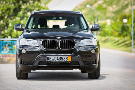 GRODNO, BELARUS - JUNE 2020: BMW X3 II F25 2.0i xDrive selective focus front view outdoors on sunny road background of summer city promenade flowering chestnuts landscape with copyspace.のeditorial素材