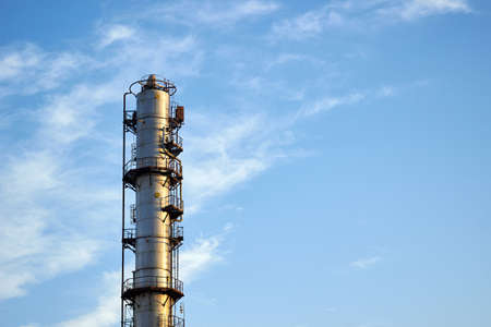 Old distillation column towers with blue sky with clouds background at chemical plant. Exterior of silver metal rusty methanol distillation enterprise with copyspace .の写真素材