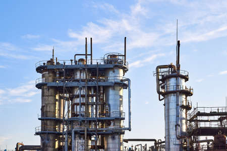 Old distillation column towers with blue sky with clouds background at chemical plant. Exterior of silver metal rusty methanol distillation enterprise with copyspace .の写真素材