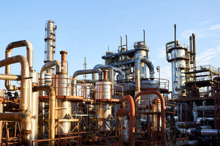 Old distillation column towers and reactors under blue evening sky background at chemical plant. Exterior of silver metal rusty enterprise with copyspace.の写真素材