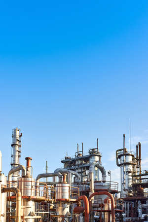Old distillation column towers and reactors under blue evening sky background at chemical plant. Exterior of silver metal rusty enterprise vertical with copyspace.の写真素材