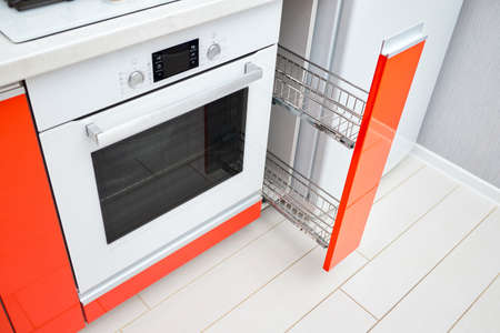 Upscale Maple Red kitchen spice rack drawer vertical cabinet. Pull out spice rack cabinet filler pantry near oven and fridge. Vertical drawer for spices shelf with orange front panels horizontal.の写真素材