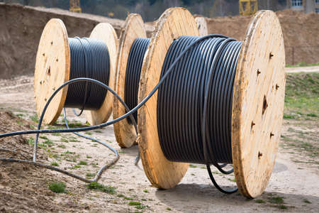 Concept of electricity supply for construction projects. Several wooden coils with power cable laid in trench.の写真素材