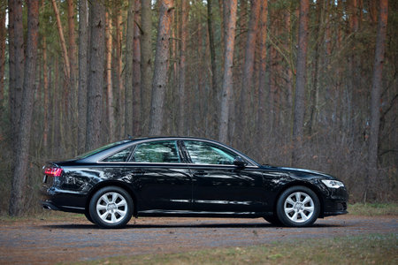 GRODNO, BELARUS - DECEMBER 2019: Audi A6 4G, C7 2.0 TDI 190 Hp 2016 black metallic right side view outdoors on winter empty road with forest on backgroundのeditorial素材