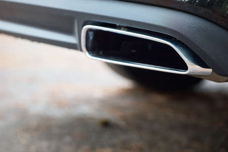 Chrome exhaust pipe of powerful luxury car selective focus with black bodywork as part of exhaust system car muffler of modern new car with out of focus background with copyspace.の写真素材