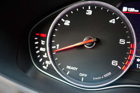 Rev counter of car selective focus closeup with copyspace.Tachometer or revolution counter, RPM gauge with red glowing needle on car dashboard with fuel and engine temperature indicators.の写真素材