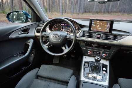 GRODNO, BELARUS - DECEMBER 2019: Audi A6 4G C7 interior in dark tones with display with GPS navigation map multimedia system climate control panels example of modern vehicle technological equipment.のeditorial素材
