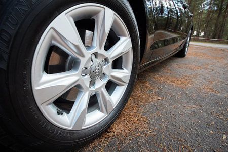 GRODNO, BELARUS - DECEMBER 2019: Audi A6 4G C7 Luxury car closeup alloy wheel with Dunlop winter tires side view with titanium look matt finish with fall forest background.のeditorial素材