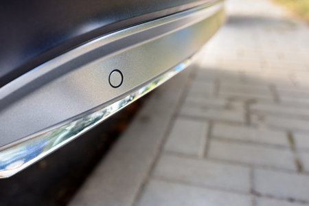 Selective focus on rear bumper left side parking sensor at back of luxurious car bumper close up on...