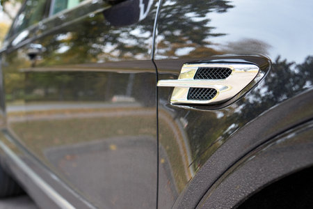 BERLIN, GERMANY - OCTOBER 2020: Bentley Bentayga Hybrid SUV bodywork metallic surface of racing vehicle body detail of door wing fender and air intake with Bentley logo shaped grill with copyspaceのeditorial素材