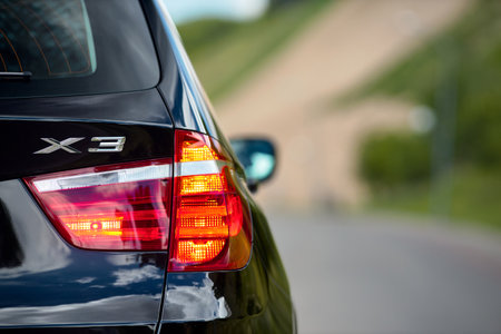 GRODNO, BELARUS - JUNE 2020: BMW X3 II F25 xDrive Black car right rear clear glass led taillight turn on signal reversing lights and emergency lights luminous closeup selected focus with copyspace.のeditorial素材