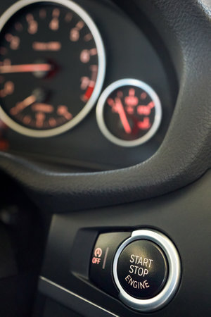 Selective focus on red enlightened Car Start Stop Engine Button. Element of interior inside car, vertical with copy space.の写真素材