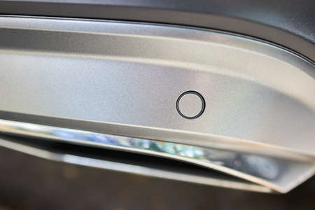 Selective focus on bumper right side parking sensor at back of luxurious car bumper close up on light blurred with sun flare background with copyspace.の写真素材