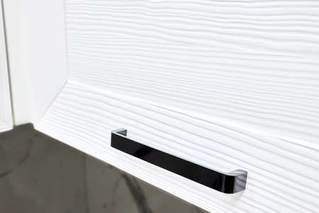 Concept of home kitchen storage organized cabinetry drawer or cupboard door handle furniture. Steel rectangular black knob selective focuse on brushed white oak panel kitchen cabinet or cupboard.の写真素材