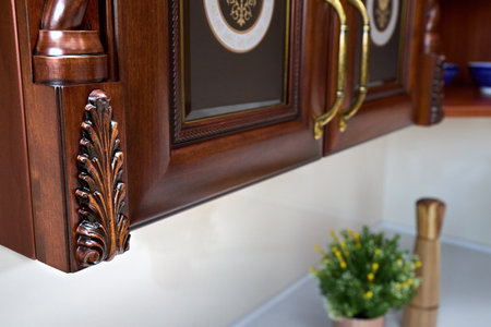 Selective focus fragment of cherry alder wooden cabinetry kitchen, carved detail. Carved decorative detail. Wooden pilasters. Decor furniture. Carved decor elements. Decorative elements.の写真素材