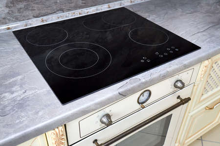 Modern kitchen luxurious interior with black induction or electric hob stove cooker with ceramic top surface with marble countertop and wall decorated with stone.の写真素材