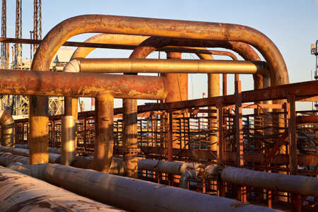 Tangle of gas collector steel pipes rust covered with traces of corrosion and aging. Concept of complexity of petrochemical industry communications. Various diameters pipe weaving valves and flangesの写真素材