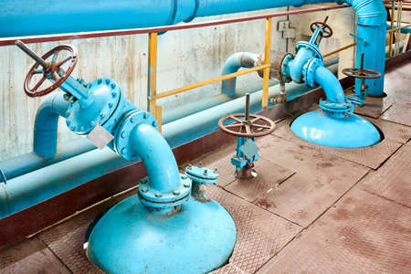 Petrochemical plant interior. Two blue valves with brown red steering wheels over background of pipes buffer reactors and collector inside chemical plant.の写真素材