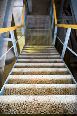 Example of chemical plant steampunk retro style interior part with copyspace. Abstract image of industrial textured rusted stairs going down vertical.の写真素材
