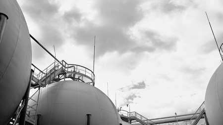 Industrial landscape bottom up view on several spherical gasholders with lightning protection and safety valve on modern chemical production. Black and white 16x9 industrial petrochemical background.の写真素材