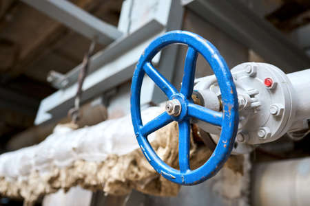 Industrial pipeline blue hand wheel flanges and valve close up, selective focus industrial pipelines background. Old rusty technological petrochemical equipment, abandoned plant with copyspace.の写真素材