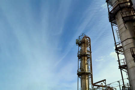 Oil refinery chemical plant bottom view with copyspace over blue evening sky with clouds background. Methanol production distillation refinery columns industrial background.の写真素材