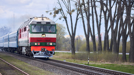 Grodno, Belarus - April 2021: passenger train with diesel locomotive moves on standard gauge railway...