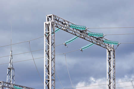 High voltage electric glass insulator of electric high voltage electric transmission power tower and lightning protection mast over cloudy stormy dark sky.の写真素材
