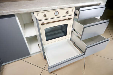 Solution for placing kitchen utensils in modern kitchen. Horizontal sliding pullout drawer shelves storage in cupboard for kitchenware under uven and porcelain stoneware countertop horizontal.の写真素材
