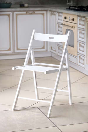 Bright white comfortable simple wooden folding chair out of focus interior kitchen background.の写真素材