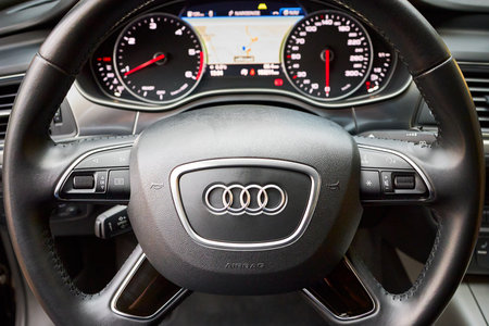 GRODNO, BELARUS - DECEMBER 2019: Audi A6 4G C7 steering wheel with audi logo with out of focus car dashboard display navigation GPS system with map radio fuel weather heat tachometer and speedometerのeditorial素材