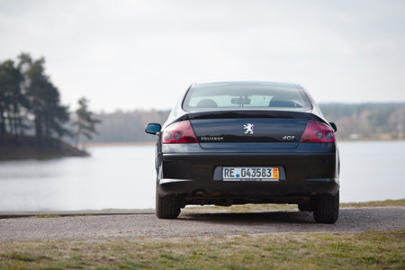 Berlin - April 2014: Peugeot 407 2003-2010 sedan pre facelift rear view on road outdoors over spring landscape background with lake and forest with copyspace.のeditorial素材