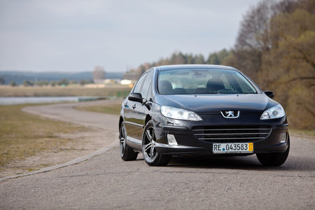 Berlin - April 2014: Peugeot 407 2003-2010 sedan pre facelift three quarter view on road outdoors over spring landscape background with lake and forest with copyspace.のeditorial素材