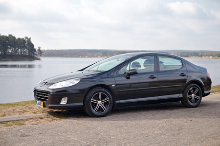 Berlin - April 2014: Peugeot 407 2003-2010 sedan pre facelift three quarter side view on road outdoors over spring landscape background with lake and forest with copyspace.のeditorial素材