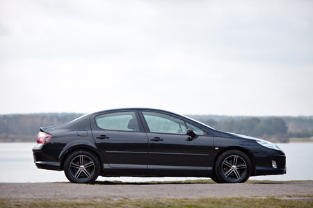 Berlin - April 2014: Peugeot 407 2003-2010 sedan pre facelift side view on road outdoors over spring landscape background with lake and forest with copyspace.のeditorial素材