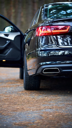 GRODNO, BELARUS - DECEMBER 2019: Audi A6 4G, C7 2016 Left back rearlight of black metallic car shot closeup with opened door out of focus on forest background with copyspace 16x9.のeditorial素材