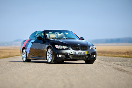 Berlin - April 2014: : BMW 3 series E93 328i convertible with m-pack logo stripes outdoors. Open roof cabrio. BMW cabriolet 3-series in field country road under spring blue sky with copyspace.のeditorial素材