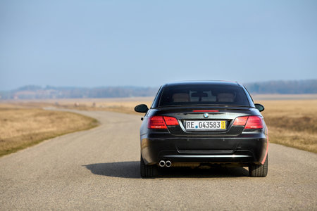 Berlin - April 2014: : BMW 3 series E93 328i convertible with m-pack logo stripes outdoors. Rear back view. BMW cabriolet 3-series in field country road under spring blue sky with copyspace.のeditorial素材