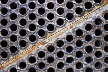 Tube sheet plate of heat exchanger or boiler closeup texture macro diagonal background with insoluble hard mineral deposits salts scale welding seams and corrosion. Trypophobia concept.の写真素材