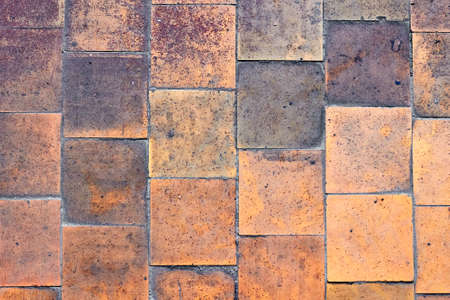 Orange brown purple old shabby worn out floor tiles with damages cracks dirt caverns potholes and paint stains. Art design background texture.の写真素材