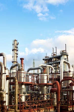 Old distillation column towers absorbers and reactors under blue evening cloudy sky background at chemical plant. Exterior of silver metal rusty enterprise vertical with copyspace.の写真素材