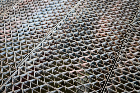 Metal industry steel grade sheet. Shallow depth of field diminished perspective industrial grates profiled drainage latticed metal flooring. Ffloor grating at petrochemical plant.の写真素材