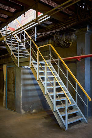 Industrial building structure fragment featuring metal staircases and pillars. Abstract image on the subject of modern architecture, industry and technology.の写真素材