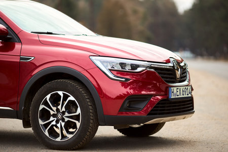 Berlin - March 2022: 2021 Renault Arkana e-Tech hybrid SUV car three fourth right front side view outdoors parked on street near forest.のeditorial素材